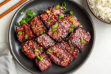 thinly sliced char siu pork with a deep red caramelized glaze, arranged on a plate with jasmine rice. Chinese food. 