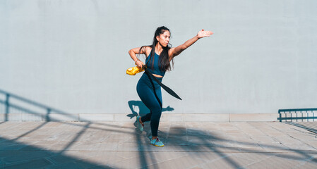 Chinese young woman practicing wushu kung fu with weapons outdoor. Young girl training martial arts...