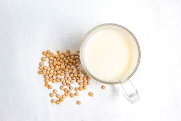 glass of soy milk and soy beans on white background