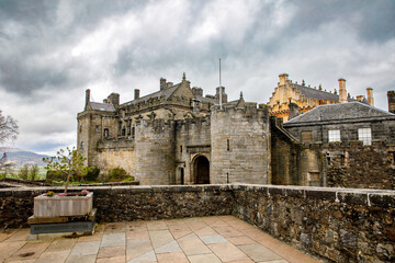 Obraz premium Stirling Castle in Scotland, a historic fortress with stone walls, towers, and scenic countryside views beneath dramatic cloudy skies