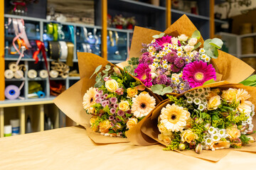 Colorful flower bouquets wrapped in brown paper resting on table in flower shop