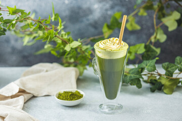 Glass of iced matcha latte with whipped cream and a straw is refreshing