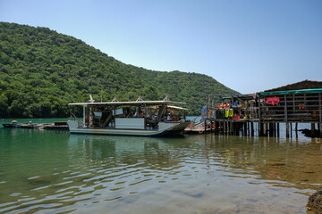 Fototapeta premium Floating seafood farm with a docked boat in a green bay