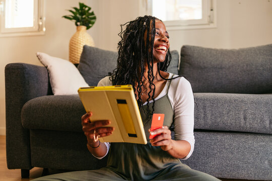 Smiling woman shopping online using digital tablet and credit card at home