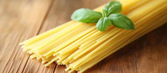 Dried spaghetti noodles with fresh basil leaves on a rustic wooden surface for culinary and food styling concepts.