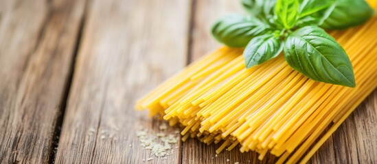 Close-up of uncooked spaghetti pasta with fresh basil leaves on a rustic wooden background for culinary or recipe themed designs.