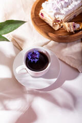 mille-feuille cake on a wooden plate with coffee and blue flowers, food photo, light composition, French cuisine, French dessert, low-calorie cake