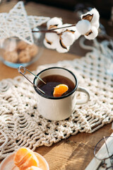 black tea in a white mug, tea with tangerine on a wooden background in sunny morning light, macrame napkin