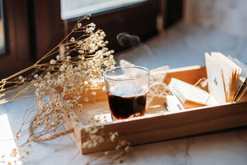 coffee in a glass cup in the morning sunlight on the windowsill, gypsophila flowers, white flowers, open book, morning coffee
