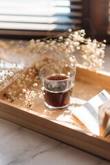 coffee in a glass cup in the morning sunlight on the windowsill, gypsophila flowers, white flowers, open book, morning coffee