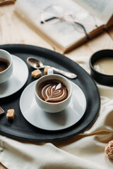 Coffee in glass cup on wooden background, espresso coffee in double-bottomed glass cups, cane sugar, open book, coffee on a black tray, lunch break, coffee still life close-up