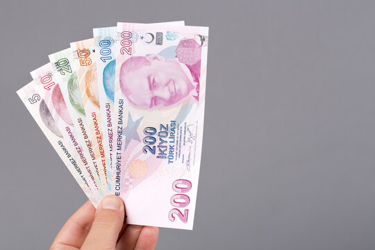 Turkish lira in the hand on a gray background