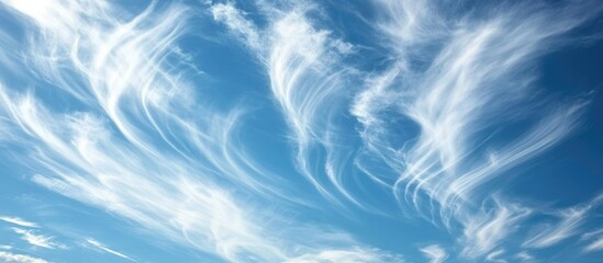 Obraz premium Elegant wisps of white clouds contrasting against a vibrant blue sky creating a serene and tranquil atmosphere for nature lovers.