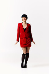 Stylish woman in bold red attire showcases modern fashion in vibrant studio setting
