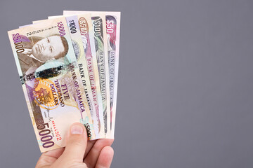 Jamaican money in the hand on a gray background