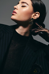 Stylish young woman showcasing elegance in a modern black suit with bold accessories