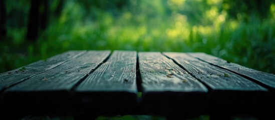 Wooden tabletop with blurred green nature background providing empty space for customizable text and designs in a serene outdoor setting