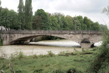 Old brick bridge over the river, greenery and trees around.