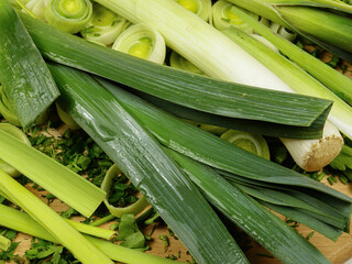 Whole and cut, peeled and unpeeled leek and celery lie on a chopped dill and parsley
