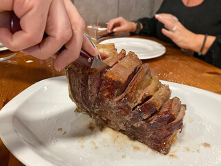cortando una chueta de vaca chuletón de ternera buey asada con sal carne en un plato lista para...