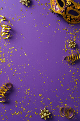 Flat lay carnival masks with golden tinsel on purple background. Venice carnival, Mardi Gras, masquerade concept. © photoguns