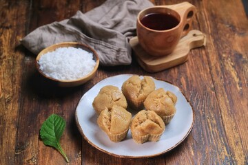 Kue Apam Gula Merah or Kue Apem or Kue Mangkok, Indonesian traditional steamed cake made from brown sugar served with grated coconut on a plate.
