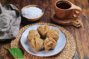 Kue Apam Gula Merah or Kue Apem or Kue Mangkok, Indonesian traditional steamed cake made from brown sugar served with grated coconut on a plate.
