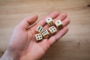 Hand holding six dice on wooden background