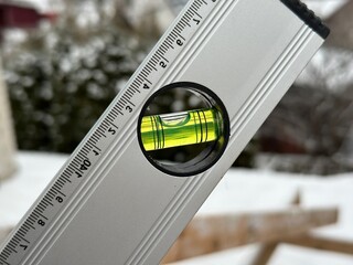 A spirit level displays a bubble perfectly centered, indicating straight alignment in a snowy...