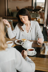 Two Women Enjoying Tea and Desserts in a Cozy Cafe Setting