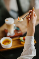 Close-Up of Hand Holding Spoon with Dessert at a Cozy Cafe Table