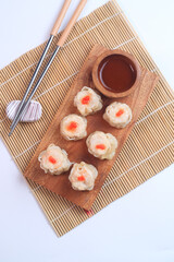 chicken dimsum served in a plate with chopstick and sauce