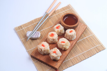 chicken dimsum served in a plate with chopstick and sauce