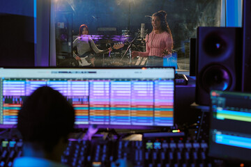 Talented girl band recording new album at professional studio, vocalist discussing details with...