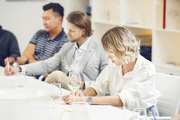 Obraz premium Sommeliers tasting wine at table indoors. Alcoholic beverages degustation courses. Winemaking school, wine waiter certification.