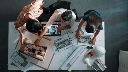 Top view of project manager working together to brainstorm house design while standing around...