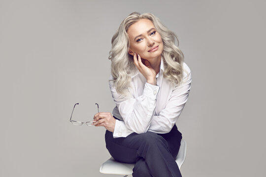 Beautiful mature woman on a gray background, dressed in a strict classic style.