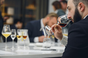 Professional sommelier sniffing various alcoholic drink during blind tasting. Sommelier exam to...
