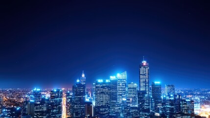 Obraz premium A stunning night view of a vibrant city skyline, illuminated by twinkling lights against a deep blue sky, showcasing modern skyscrapers and urban beauty.