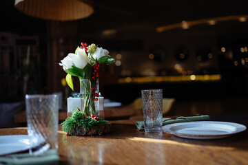 Bunch of flowers composition on the table in elegant cafe. Beautifully arranged table decoration with rose flowers in glass bottle.