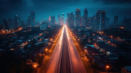 Fototapeta premium Aerial view of the highway running through the city at dusk. Urban landscape with modern skyscrapers and residential areas along the road
