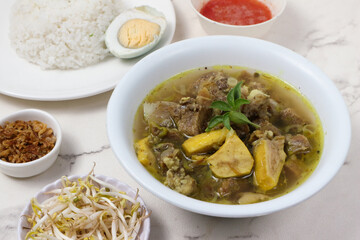 Delicious Indonesian Sop Buntut: A savory beef tail soup, served with rice, boiled egg, bean sprouts, and crispy fried shallots.