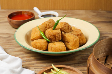 Delicious Fried Tofu with Chili Garnish, Served on a Rustic Wooden Table