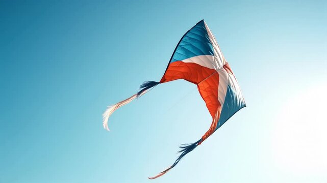 Colorful kite with red, white, and blue patterns flying against a clear sky on a sunny day.
