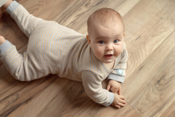 Naklejka premium Tummy and crawling time.portrait of a cute cheerful Caucasian child on the floor in a nursery