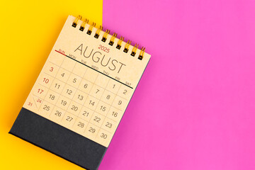 August 2025 desk calendar made from brown paper page on multicolor background.