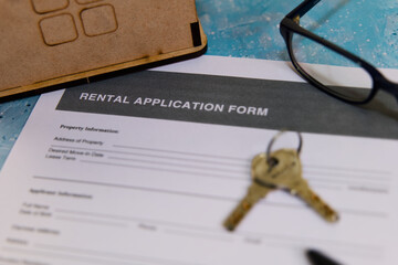 Rental application form with keys and glasses on table
