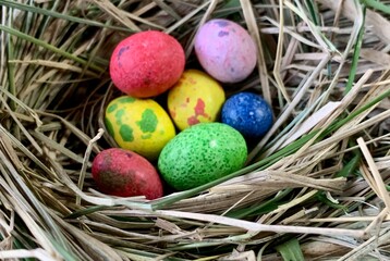 Brightly colored eggs in shades of red, yellow, blue, green, and pink rest in a cozy nest made of straw, symbolizing the joys of spring and Easter celebrations