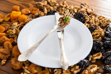 Clean empty plate and Nuts, dried apricots and prunes on a wooden table