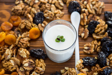 natural yogurt with nuts, dried apricots and prunes on a wooden table